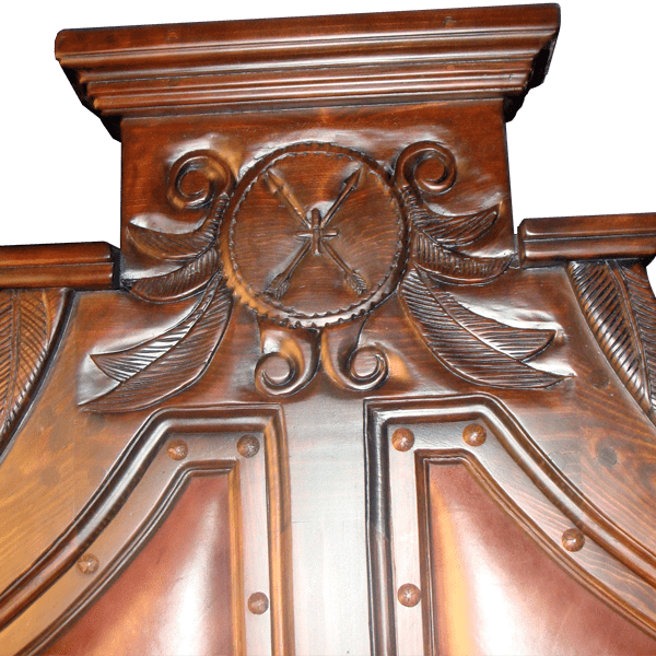 Detail of headboard carving with arrows, feathers, scrolls, and central cross