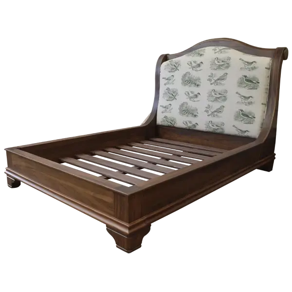 Semi-front view of Spanish colonial bed with patterned fabric headboard and solid wood frame